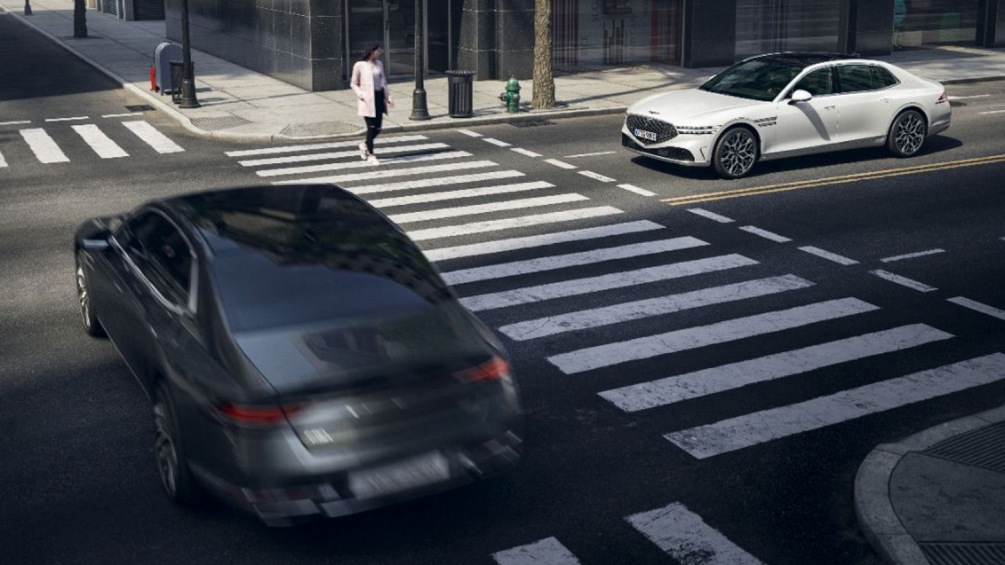 Eine Szene, die die Sicherheitsfunktionen des G90 zeigt, während er einen Fußgänger an einem Zebrastreifen in der Stadt erkennt.